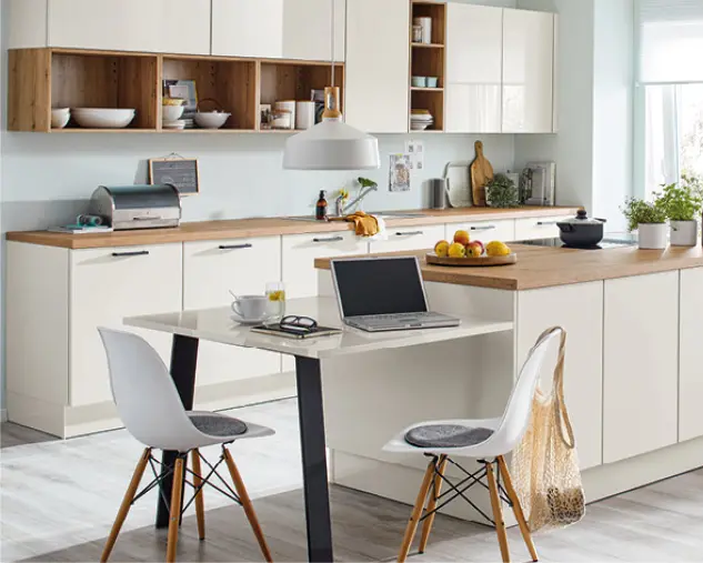 Helle Wohnküche mit weißer Küchenzeile, Holzarbeitsplatten und Kücheninsel mit Sitzplätzen, Laptop und Obstschale, ideal für Kochen, Arbeiten und gemeinsames Wohnen im modernen Küchenstil.